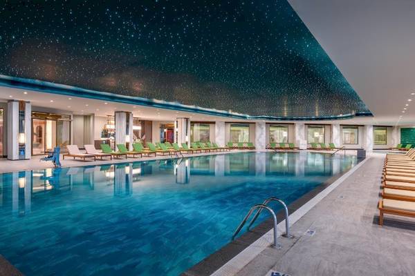 Poolbereich im Delphin Palace Hotel mit Sternenhimmeldecke und grünen Liegen