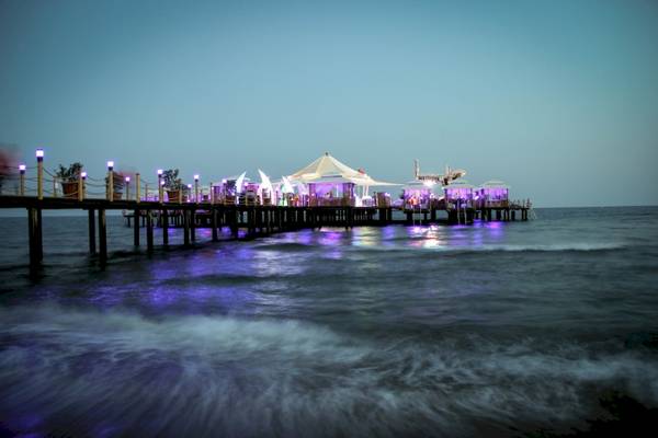 Beleuchteter Pier des VONRESORT Golden Coast bei Nacht mit weißen Zelten und blauen Lichtern.