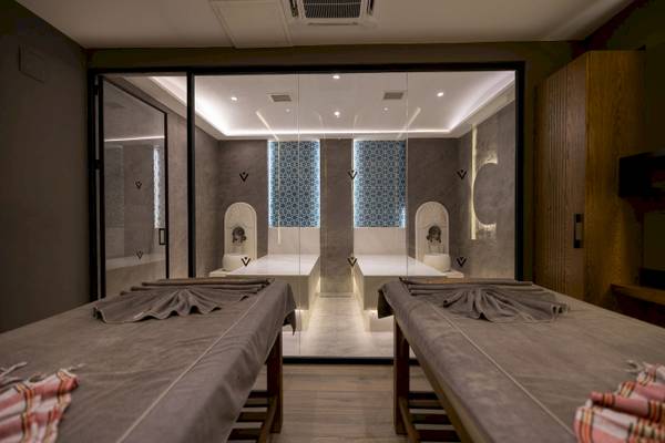 Spa-Behandlungsraum im VONRESORT Golden Coast mit zwei Massagetischen und Glaswänden.