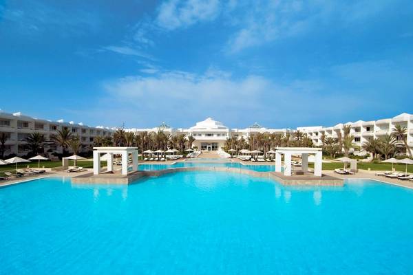 Außenbereich des Radisson Blu Palace Resort & Thalasso, Djerba, mit einem großen Swimmingpool und Sonnenliegen.