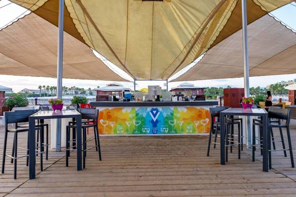 Barbereich des VONRESORT Golden Coast mit bunter Wand und Tischen und Stühlen unter einem Sonnensegel.