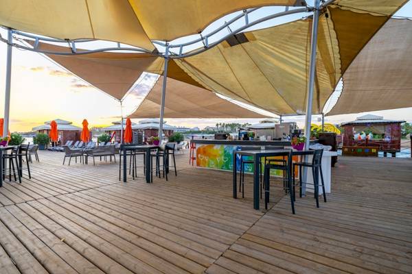 Terrasse des VONRESORT Golden Coast mit Tischen, Stühlen und Sonnenschirmen bei Sonnenuntergang.