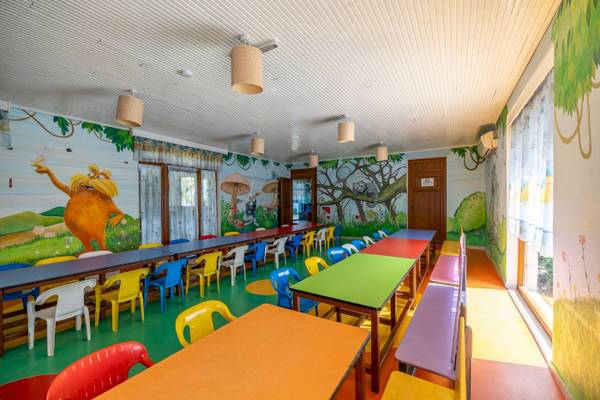Vonresort Golden Coast Kinderzimmer mit bunten Tischen und Stühlen und illustrierten Wänden.
