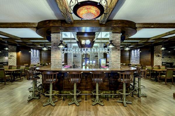 Innenansicht der Bar im VONRESORT Golden Coast mit runden Holztischen und Stühlen.