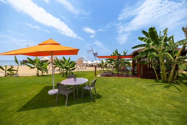 Außenbereich des VONRESORT Golden Coast mit Tisch, Stühlen und Sonnenschirm am Strand