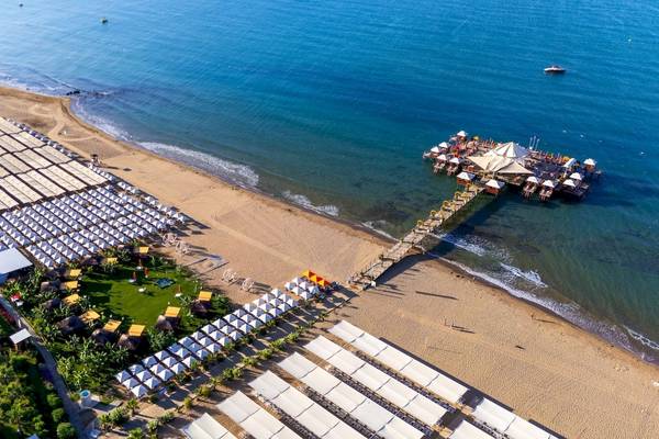 Luftaufnahme des VONRESORT Golden Coast mit vielen weißen Sonnenschirmen am Strand und einem Steg zum Meer.