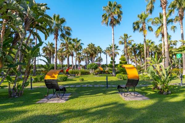 Gartenlandschaft des VONRESORT Golden Coast mit gelben Liegestühlen und Palmen
