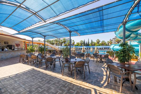 Terrasse des VONRESORT Golden Coast mit Tischen, Stühlen und blauen Markisen.