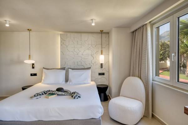 Georgioupolis Resort Aquapark & SPA Zimmer mit Bett, weißem Stuhl und Fenster mit Aussicht auf den Berg.