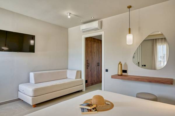 Innenansicht der Suite im Georgioupolis Resort Aquapark & SPA mit weißem Sofa, Fernseher und Dekogegenständen.