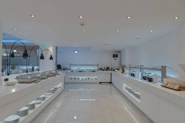 Innenansicht des Restaurants im Georgioupolis Resort Aquapark & SPA Hotel mit weißen Tischen und Buffets.