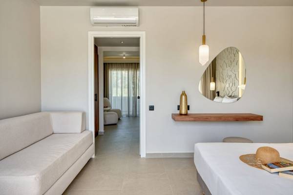 Innenansicht eines Zimmers im Georgioupolis Resort Aquapark & SPA mit Sofa, Bett, Spiegel und Dekoration.