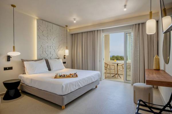 Innenansicht eines Hotelzimmers im Georgioupolis Resort Aquapark & SPA mit Bett, Frühstückstablett, Tisch und Balkon.