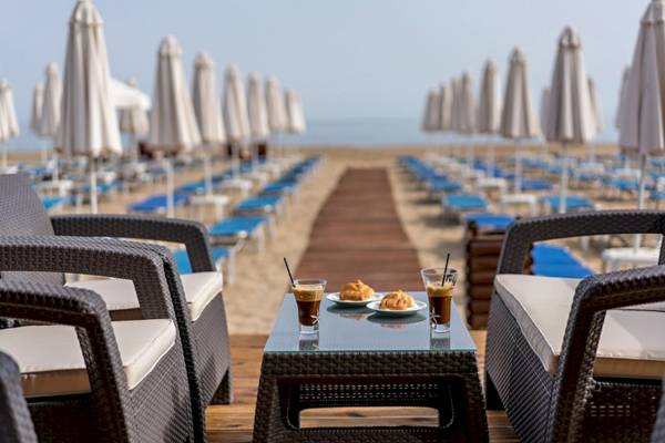 Georgioupolis Resort Aquapark & SPA Terrasse mit Tisch, Getränken und Sonneliegen.