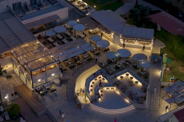 Abendluftaufnahme des Georgioupolis Resort Aquapark & SPA mit beleuchteten Terrassen und Gästen.