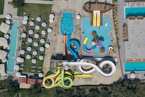 Luftaufnahme des Georgioupolis Resort Aquapark & SPA mit Pools, Rutschen und Sonnenschirmen.