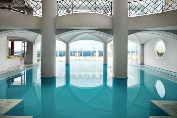 Innenpool des Mitsis Summer Palace Hotels mit blauem Wasser und weißen Säulen.