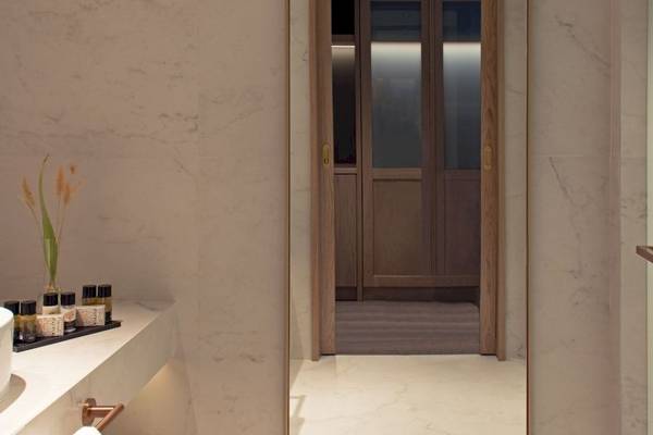 Badezimmer im Mitsis Summer Palace mit Marmorwänden und offenem Türgang zu einem Kleiderschrank.