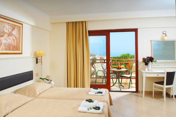 Doppelzimmer mit Balkon im Cactus Village Hotel & Bungalows mit Blick auf den Garten und den Tisch draußen.