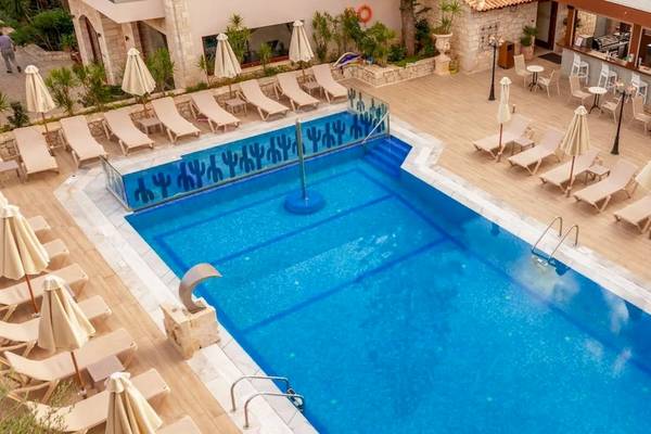 Außenbereich eines Hotels mit Swimmingpool, Liegen und Sonnenschirmen.