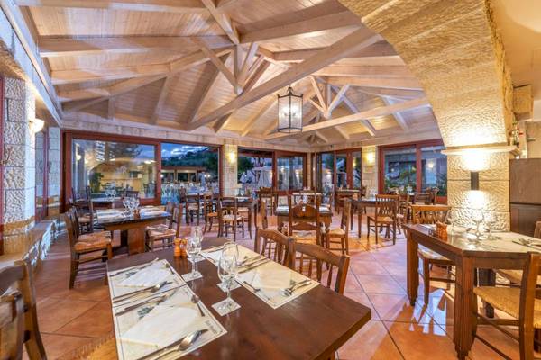 Innenbereich des Restaurants im Cactus Village Hotel & Bungalows mit Holztischen und Stühlen.