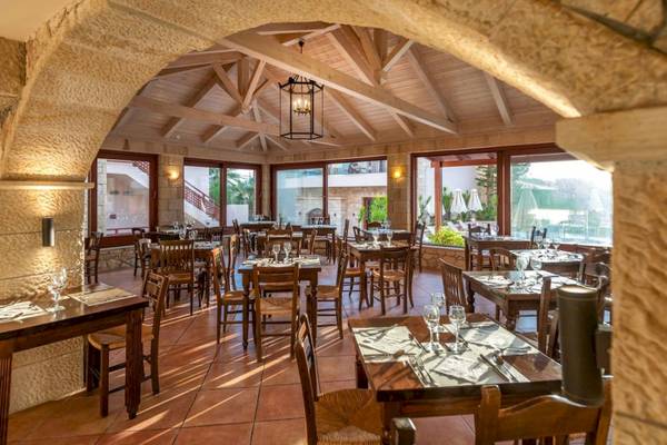Innenbereich des Cactus Village Hotel & Bungalows Restaurants mit Holztischen und Stühlen.