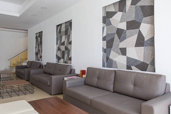 Loungebereich im Sun Palace Hotel mit grauen Ledersofas, geometrischen Wandteppichen und modernen Couchtischen.