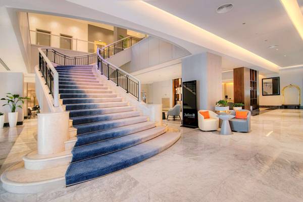 Lobbyansicht des Radisson Blu Hotel & Resort in Abu Dhabi Corniche mit einer großen Treppe und Möbeln.