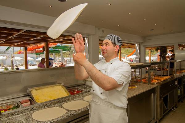 Koch im Sun Palace Hotel wirft Pizza-Teig in die Luft.