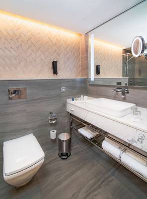 Badezimmer im Radisson Blu Hotel & Resort, Abu Dhabi Corniche mit grauen Wänden, Marmor-Waschtisch und Toilette.
