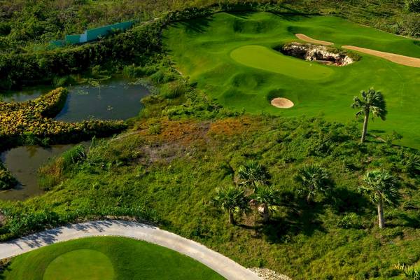 Golfplatz mit sternförmigem Wasserlauf und Palmen, gesehen von oben.