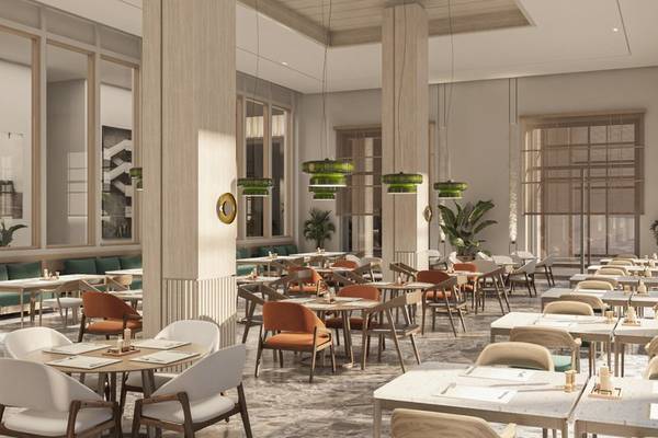 Innenansicht des Restaurants im Jaz Elite Amara Hotel mit runden Tischen und Stühlen, grünen Pflanzen und Kronleuchtern.
