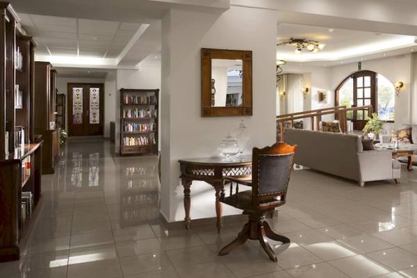 Empfangsbereich des Almyrida Beach Hotels mit gefliestem Boden, Couch, Tisch und Bücherregal.