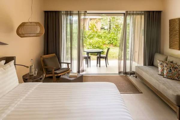 Schlafzimmer im Constance Ephelia Resort mit Blick auf den Garten und einem Tisch mit Stühlen.