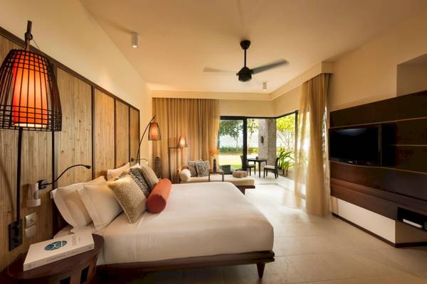 Luxuriöses Schlafzimmer im Constance Ephelia Resort mit Bett, Sofa, Tisch und Fernseher.