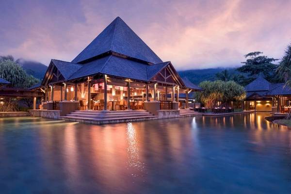 Nachtansicht des Constance Ephelia Resorts mit blauem Dach und Pool