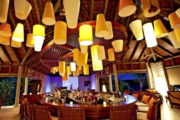 Die Bar im Constance Ephelia Resort mit vielen gelben Lampen an der Decke.