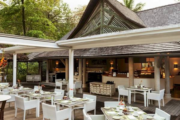 Außenbereich des Constance Ephelia Resorts mit Tisch und Stühlen, umgeben von Pflanzen.