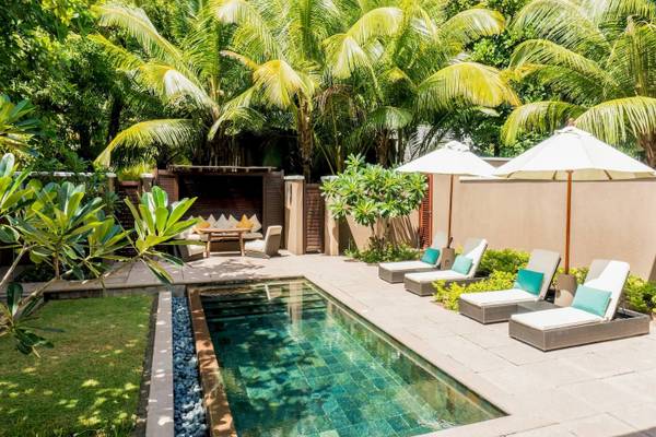 Außenbereich des Constance Ephelia Resorts mit Pool, Liegestühlen und Sonnenschirmen.