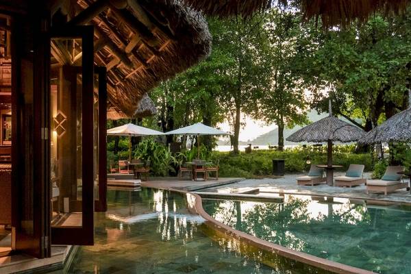 Außenbereich des Constance Ephelia Resorts mit Pool, Sonnenschirmen und Loungemöbeln.