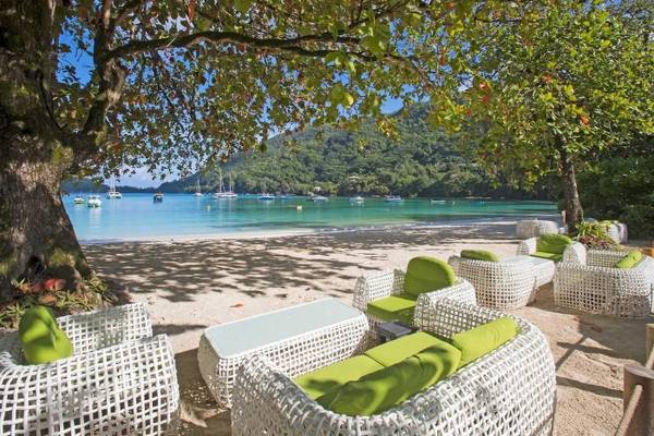 Lounge-Set am Strand des Constance Ephelia Resorts mit Blick auf das Meer und Berge.