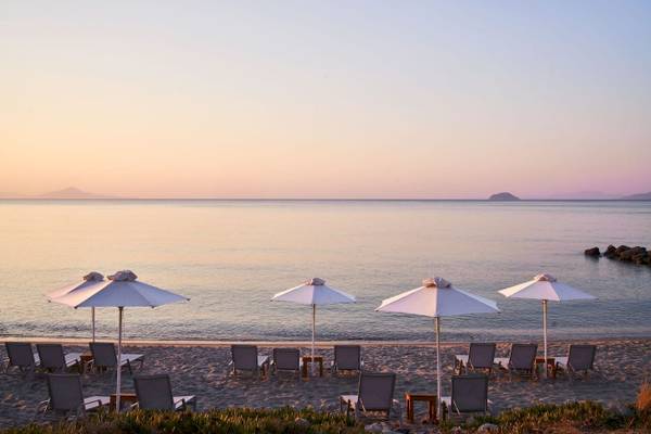 Sonnenuntergang am Strand des Atlantica Beach Resort Kos mit Sonnenschirmen und Liegen