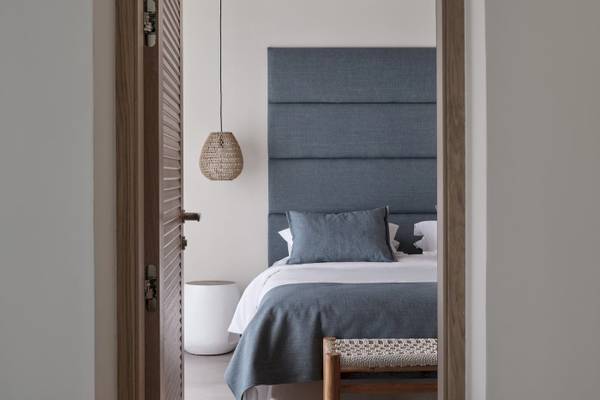 Zimmer im Atlantica Beach Resort Kos mit einem Bett, blauem Kopfteil und einem weißen Stuhl.
