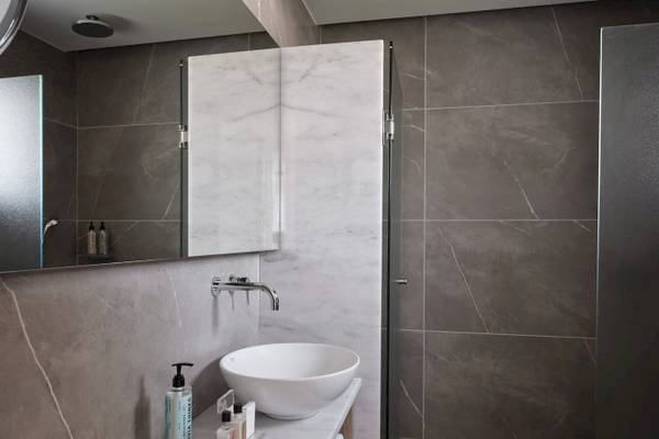 Badezimmer im Atlantica Beach Resort Kos mit grauen und weißen Fliesen und einem weißen Waschbecken.