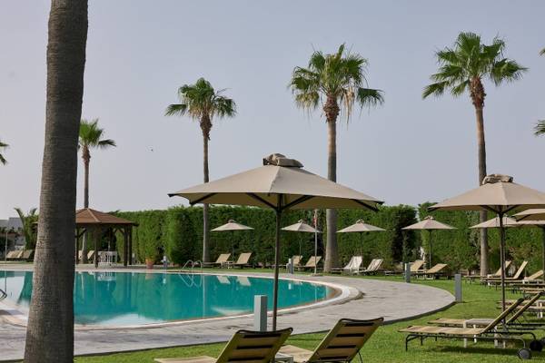 Poolbereich des Atlantica Beach Resort Kos mit Sonnenliegen und Sonnenschirmen.