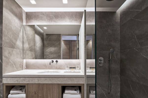 Modernes Badezimmer im Atlantica Beach Resort Kos mit grauen Marmorwänden und einer großen Spiegelfläche.