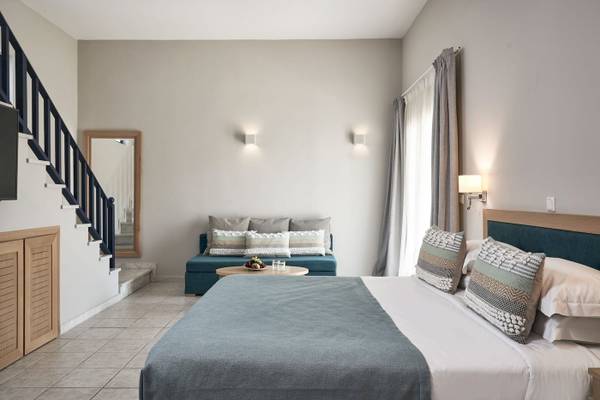 Schlafzimmer im Atlantica Beach Resort Kos mit einem Bett, einem Couchtisch, einer Kommode und einer Treppe.
