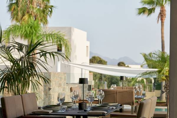 Restauranttisch im Atlantica Beach Resort Kos mit Blick auf Palmen und Gebäude.