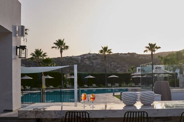 Abendlicher Blick auf den Pool des Atlantica Beach Resort Kos mit Cocktails und Palmen.