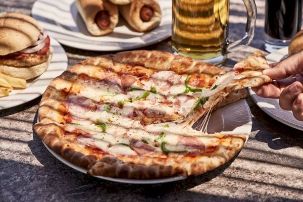 Tisch mit einer geschnittenen Pizza, Bier, alkoholfreien Getränken und Sandwiches.
